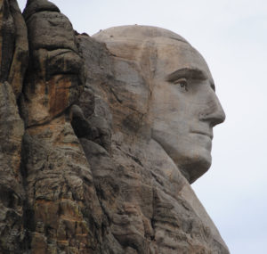   Close‑up view of George Washington’s carved face on Mount Rushmore, showing detailed granite texture and sculpted features against the rock surface.