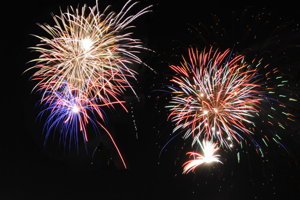 Vibrant Fourth of July fireworks lighting up the night sky with red, blue, and gold bursts.