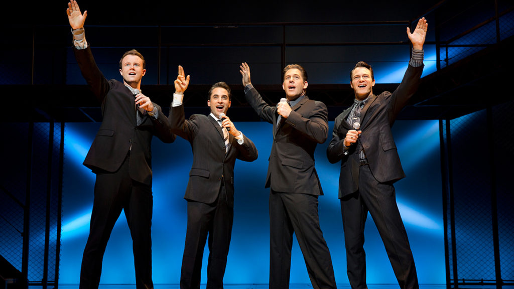 Stage performance of four singers in dark suits under blue lighting, recreating a classic Jersey Boys–style musical moment in Las Vegas.