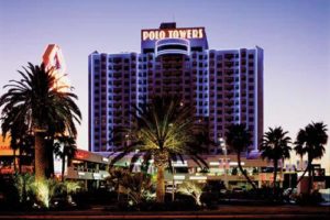   
Dusk view of the Polo Towers building on the Las Vegas Strip, with exterior lighting and palm trees in the foreground.