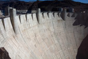 Wide view of Hoover Dam’s curved concrete structure set against rocky desert mountains on the Nevada–Arizona border.