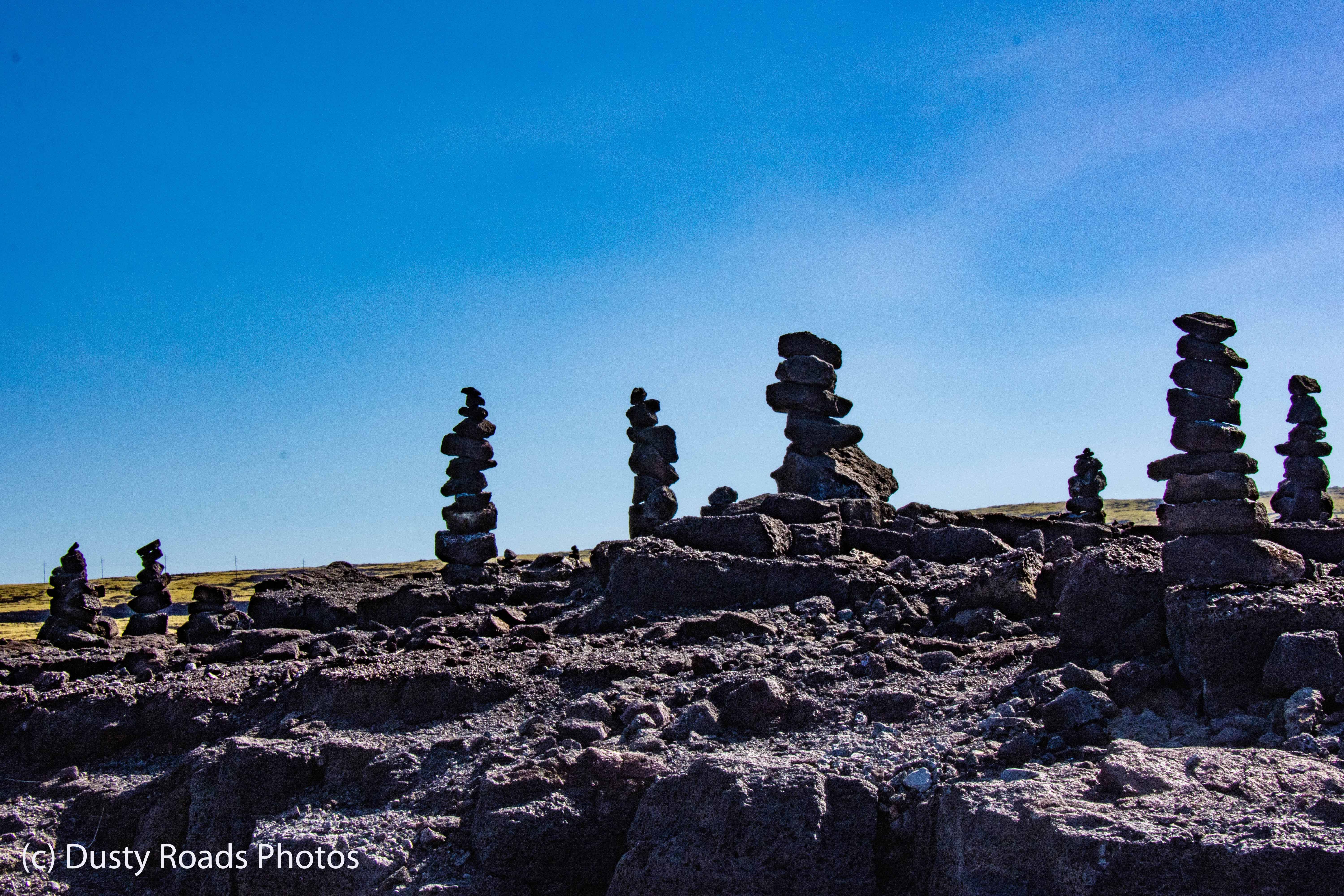 They’re trail markers, not art projects — cairns on Hawaiian lava flows are intentionally built stone piles used to guide hikers across terrain where the trail would otherwise disappear.