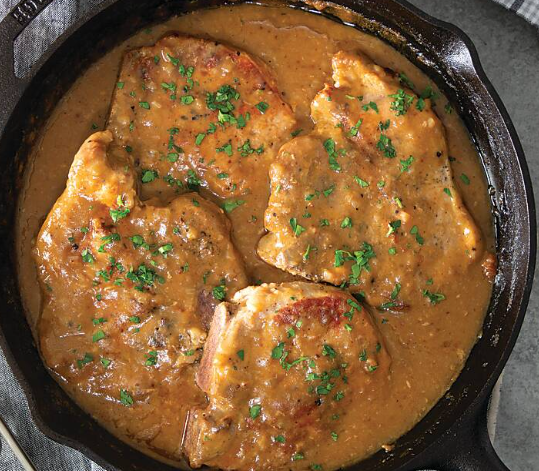 Smothered pork chops surrounded by gravy. Of course it's in a cast iron skillet