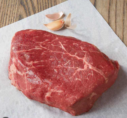 Raw sirloin steak prepared for a reverse‑sear recipe, shown with garlic on parchment.