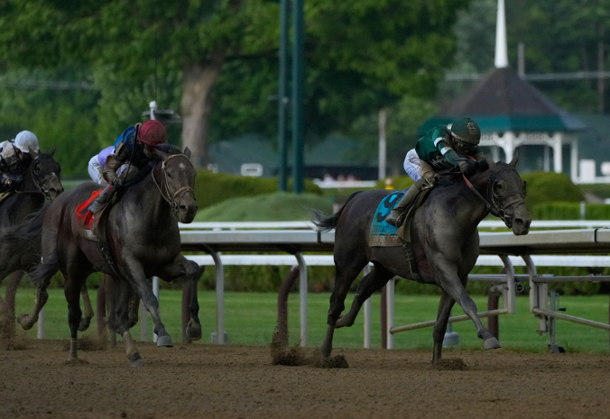 Golden Tempo surges across the Belmont finish line ahead of his rivals on a dirt track.