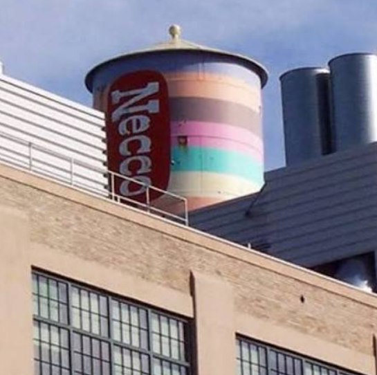 The former Necco candy factory in Cambridge, Massachusetts, with its brightly colored pastel water tower displaying the classic red Necco logo — a well‑known New England landmark.