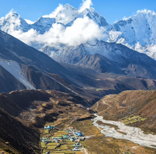 Everest Base Camp in the Himalayas, showing a remote valley village, rugged mountain terrain, snow‑capped peaks, and the iconic Everest region landscape.