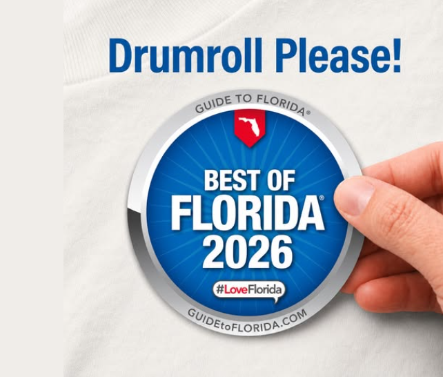 Hand holding a circular blue and silver “Best of Florida 2026” badge featuring the state of Florida icon, the Guide to Florida branding, and the hashtag #LoveFlorida, with the words “Drumroll Please!” above it.