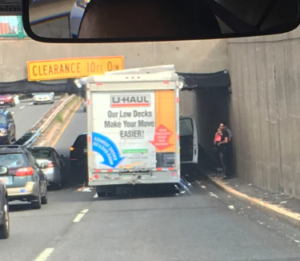U‑Haul truck wedged under a low-clearance bridge on Storrow Drive, blocking traffic during Boston’s fall move‑in season.