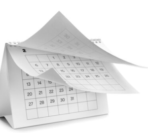 A desk calendar stands upright with its February page flipping, showing a grid of numbered days.