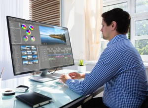 man seated at large array of monitors doing computer work