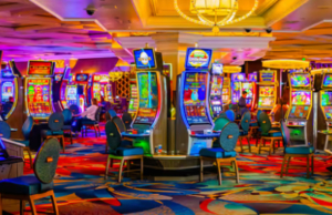   
Bright casino interior with rows of colorful slot machines, patterned carpet, and illuminated signage creating a lively Las Vegas atmosphere.