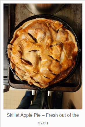 A golden‑brown apple pie baked in a cast iron skillet, with slits in the top crust and bubbling filling around the edges.