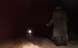  A lone figure in a long coat stands on a dark rural road at night, facing an approaching vehicle whose bright headlights illuminate the wet pavement, creating a tense, mysterious atmosphere.