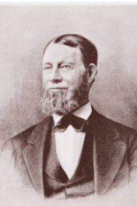   
Sepia‑toned 19th‑century portrait of Harvey Parker, shown from the chest up. He has a full beard and neatly combed hair, and wears a formal suit with a bow tie and vest, posed against a plain background in classic Victorian photographic style.